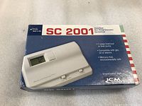 Front of the blue and white box showing the ICM SC 2001 thermostat with digital display, heat/cool switch, and key features.