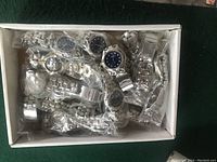 Box of new Tommy watches with blue faces and silver metal bands packed in clear plastic bags
