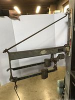 Front view of vintage metal wall mount balance scale showing the horizontal beam, weights, and mounting bracket against a white background.