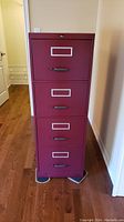 Front view of the burgundy 4 drawer filing cabinet with handles and label holders on each drawer.