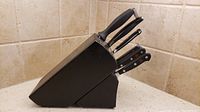 Side view of the black knife block loaded with six knives, showing different sizes and styles of blades and handles.