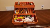 Open orange Old Pal tackle box filled with assorted fishing lures.