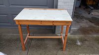 Front view of small wooden desk with solid rectangular top showing wear and stains.