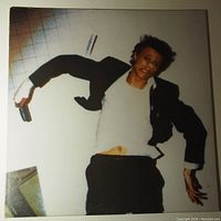 Front cover of the LP showing an image of a man (David Bowie) in black suit and white shirt lying or falling with arms and legs extended.