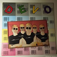 Front of vinyl LP record jacket showing Devo band members with face coverings and colorful barcode-style backdrop