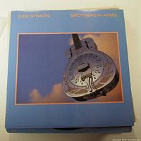 Front cover of Dire Straits Brothers in Arms vinyl LP record showing a metal resonator guitar on a blue background with the album title text in orange.