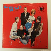 Front cover photo of The B-52s Wild Planet vinyl LP record. Shows band members on bright red background with album title and band name in top left corner.