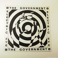 Front cover of The Government Electric Eye vinyl album featuring band members inside black and white concentric circles with text around.