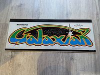 Front view of the Galaxian arcade marquee showing colorful logo and space-themed background