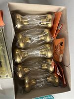 Five brass door knobs individually wrapped in plastic inside a box.
