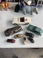Photo of all items laid out on a table showing model cars and animal figurines including elephant and hippopotamus.