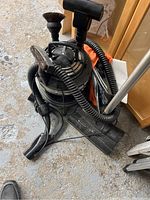 Full view of the Filter Queen vacuum with attached hoses, tubes, and multiple cleaning attachments including a brush and nozzles, placed on a carpeted floor.