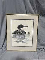 Full view of the framed painting showing a loon and chick on water with signature.