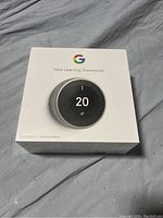 Front of sealed white retail box showing Nest Learning Thermostat and temperature UI