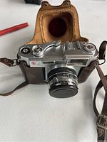 Neoca camera outside of case showing top dials, shutter, and lens with aperture numbers.