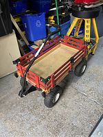 Full view of the Millside wooden kids wagon showing red wooden slats, natural wood base, black handle, and rubber tires.