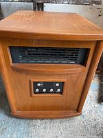 Front view of electric heater showing wood finish casing, vent, and control panel.