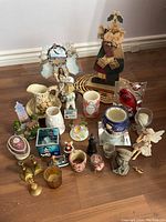 Overview of lot with various porcelain, ceramic, and metal decorative figurines, vases, bird decorations, and candle holders on floor.