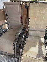 Photo of two outdoor reclining chairs side by side, showing brown fabric on one and beige woven fabric on the other.