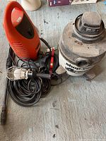 Overview of the Shop-Vac, Black & Decker pressure washer, and trouble light arranged on the floor.