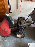 Side view of red Snow King snowblower showing the engine and tires.
