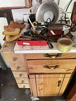Overview of vintage tools on garage counter including gloves, oil cans, hand tools, packing tape and electrical items showing worn condition and patina.