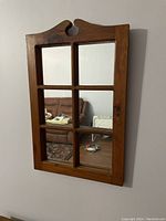 Clear image of the wooden framed wall mirror showing six mirror panes divided by muntins with a decorative top section.
