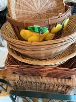 Top view showing a stack of various wicker baskets including a lemon-painted basket.