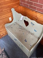 Front and side view of the wood storage bench showing the heart cutout and floral painted decoration