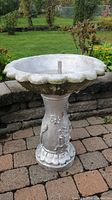 Full view of the assembled birdbath showing scalloped basin, pedestal with floral motifs, and weathered surface.