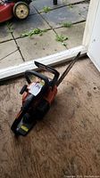 Full view of chainsaw on plywood floor near door