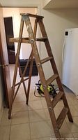 Side angled view of the wooden step ladder showing four steps and metal support brackets.