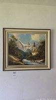 Framed original oil landscape painting showing mountains, river, church, and bridge.