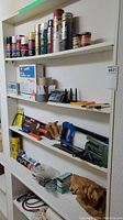 Overall view of shelves with spray paint cans, tapes, saws and hardware items