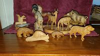 Wooden animal figurines displayed on a table including a ram, deer, buffalo, bear, beaver, lion, and smaller animals.