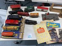 Top view of 10 vintage American Flyer model trains including engines and cars, two railroad magazines, and some train boxes visible.