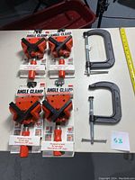 Four unopened Bessey WS 3 AC angle clamps and two Husky C clamps laid out flat with measuring tape showing scale.
