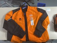 Full view of the large orange and black BMW Motorsport Puma jacket on hanger