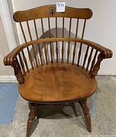 Front view of the wooden captain's chair showing the curved backrest and Brown University emblem on the top rail.