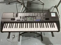 Full view of Casio CTK-720 keyboard on an X-style stand with sheet music holder attached.