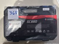 Black hard case with red label showing model SC880 and brand CGSULIT, sealed in plastic wrap with lot number.
