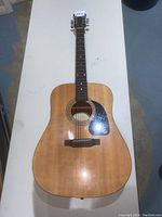 Full view of Epiphone PR-150 NA acoustic guitar with natural wood finish on body and neck, six strings, and black pickguard.