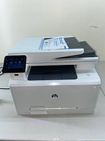 Full front view of the HP LaserJet Pro multifunction printer showing the touchscreen panel, automatic document feeder, and paper tray.