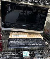 HP Pavilion 27-inch monitor with Dell wired keyboard in front, displayed on metal shelving.