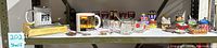 Wide shot of shelf showing assorted miniature collectibles including glassware, porcelain boxes, mugs, and keychains in group