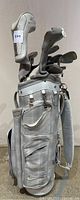 Side view of white Nike golf bag showing several zippered compartments and mesh pockets, all in white and gray tones.
