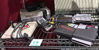 Overall view of console, controller and game cartridges on metal shelving