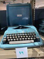 Front view of Remington Streamliner typewriter with open blue carrying case, showing keys and logo.