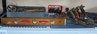 Wide shot showing all block planes, wooden level, blue wooden toolbox and assorted tools on a shelf