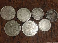 Photo showing seven antique silver coins including one 1948 Canadian sixpence with 'GRI VI' insignia and others with dated markings and floral crown designs.